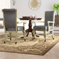 a dining room table with two chairs and a clock on the wall behind it in front of a rug