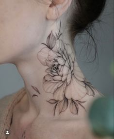 a woman's neck with a flower tattoo on it