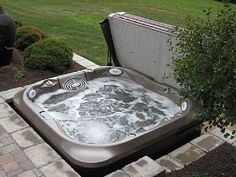 an outdoor hot tub is shown in the middle of a brick walkway and grass area