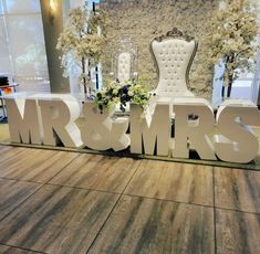 the letters mr and mrs are on display in front of an ornate chair with flowers