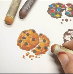 someone is drawing cookies on paper with crayons