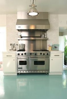 a large kitchen with stainless steel appliances and white cabinets, blue flooring is the focal point in this photo