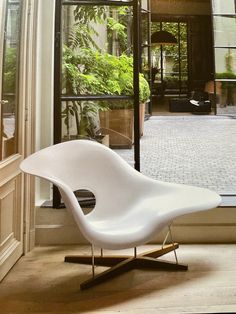 a white chair sitting on top of a hard wood floor next to a glass door