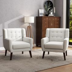 two white chairs sitting next to each other on a rug in front of a window