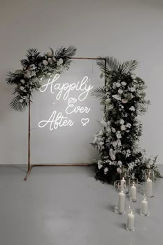 a sign that says happily ever after surrounded by candles and greenery on the floor