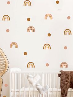 a baby's room with a crib and rainbow wall decals on the walls