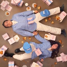 two people laying on the ground surrounded by boxes of donuts and other food items