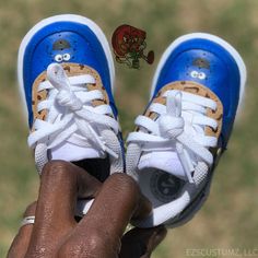 a hand holding up a pair of blue and white shoes