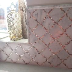 the window sill is decorated with pink and white marble tiles, along with two vases