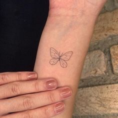 a woman's wrist with a small butterfly tattoo on her left arm and the other hand