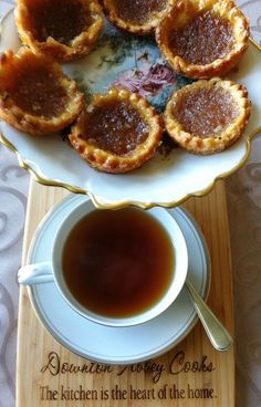 there are many small pies on the plate next to a cup of tea