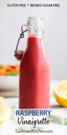 a bottle filled with raspberry vinaigrete next to sliced lemons