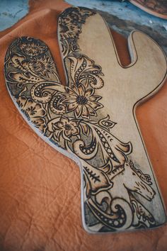 an intricately carved wooden letter on top of a leather covered tablecloth with a vase in the background