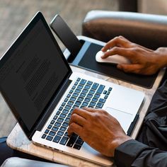 a man sitting at a table with a laptop computer and mouse in his hand, typing on the keyboard