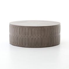 a round coffee table made out of concrete with wavy designs on the top and bottom