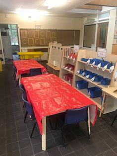 there are many tables and chairs in the room with red covers on top of them