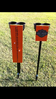 two black and orange poles with signs on them sitting in the grass next to each other