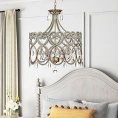 a chandelier hanging from the ceiling over a bed in a room with white walls