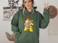 Bowser Jr Sweatshirt, Cute Bowser Jr Hoodie, Super Mario Sweatshirt, Birthday Gift,Gift for Gamer, Game Hoodie, Super Mario Bowser Jr Hoodie 🌟 Welcome! At Teekon Design, we take pride in offering you exclusive products with unique and stylish designs. Designed to keep you both comfortable and fashionable on chilly days, this sweatshirt blends comfort and style seamlessly. 🌬️ Features: High-Quality Material: Crafted from a blend of cotton and polyester, the fabric ensures durability and comfort Sporty Hoodie With Cartoon Print And Crew Neck, Sporty Crew Neck Hoodie With Cartoon Print, Super Mario Bowser, Mario Bowser, Bowser Jr, Gift For Gamer, Gaming Hoodie, Sweatshirt Cute, Gamer Gifts