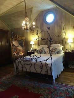 a bed room with a neatly made bed and a chandelier hanging from the ceiling