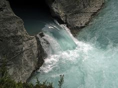 the water is blue and green as it pours into the river from the rocks