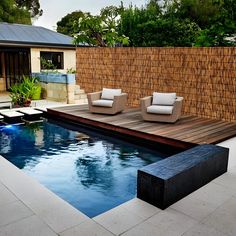 an outdoor pool with lounge chairs next to it and a wooden deck in the middle