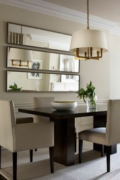 a dining room table with two chairs and a bowl on top of it in front of a mirror