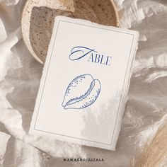 a table with a bowl, plate and napkin on it that says able written in blue ink