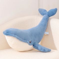 a blue whale stuffed animal sitting on top of a white couch