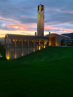 a large building with a clock on the front and side of it at night time