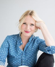 a woman sitting on the floor with her hands behind her head and looking at the camera