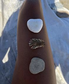 a person's foot with three stones and a leaf on it, along with two other rocks