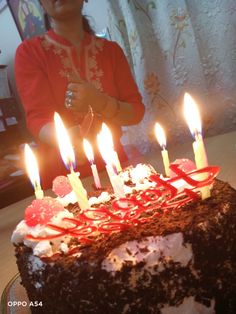 a woman standing in front of a cake with lit candles