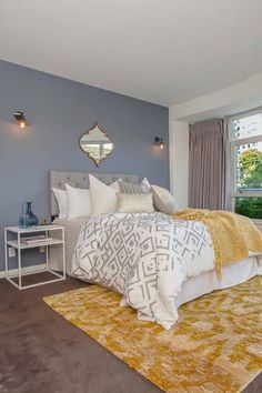 a bedroom with blue walls and carpeted flooring has a large bed in it