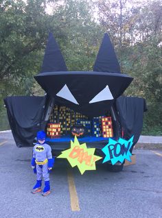 a child standing next to an inflatable car decorated like a bat and cat