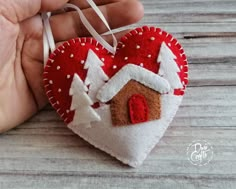 a hand holding a red and white heart shaped ornament with a house on it