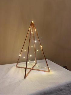 a christmas tree made out of wood and string lights on top of a white sheet