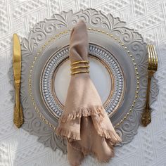 a place setting with napkins, fork and silverware on a white table cloth