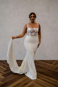 a woman in a white dress standing on a wooden floor