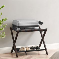 an open suitcase sitting on top of a wooden stand next to a plant and shoes