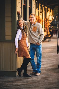 a man and woman standing next to each other in front of a building with wooden floors