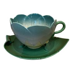 a tea cup and saucer sitting on top of a green saucer with matching saucers