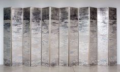 a room divider made out of metal sheeting on the floor in front of a white wall