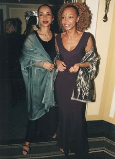 two women standing next to each other in front of a doorway with an open jacket on