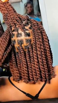 a woman with braids on her head is holding an orange object in her hand