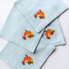 three napkins with embroidered pumpkins on them sitting next to each other in front of a white background