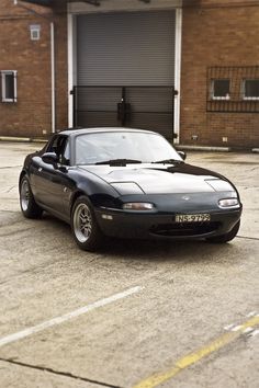 a black sports car parked in front of a garage