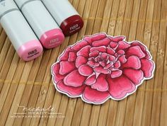 three crayon markers next to a pink flower sticker