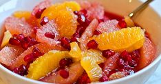 a white bowl filled with oranges and pomegranate