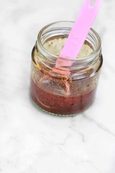 a jar filled with food sitting on top of a white marble counter next to a pink plastic fork